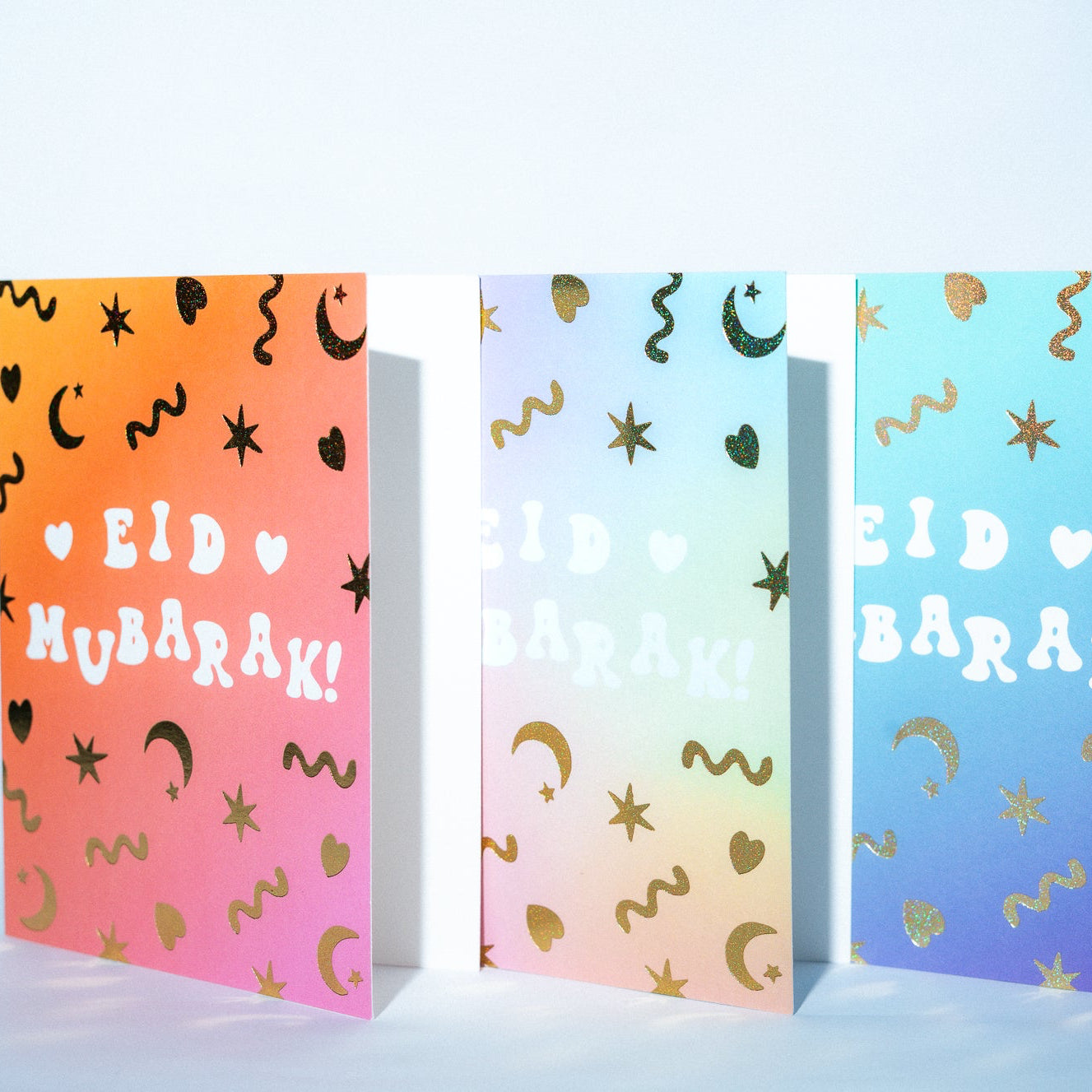 Three colorful greeting cards with 'Eid Mubarak!' text on a light blue background