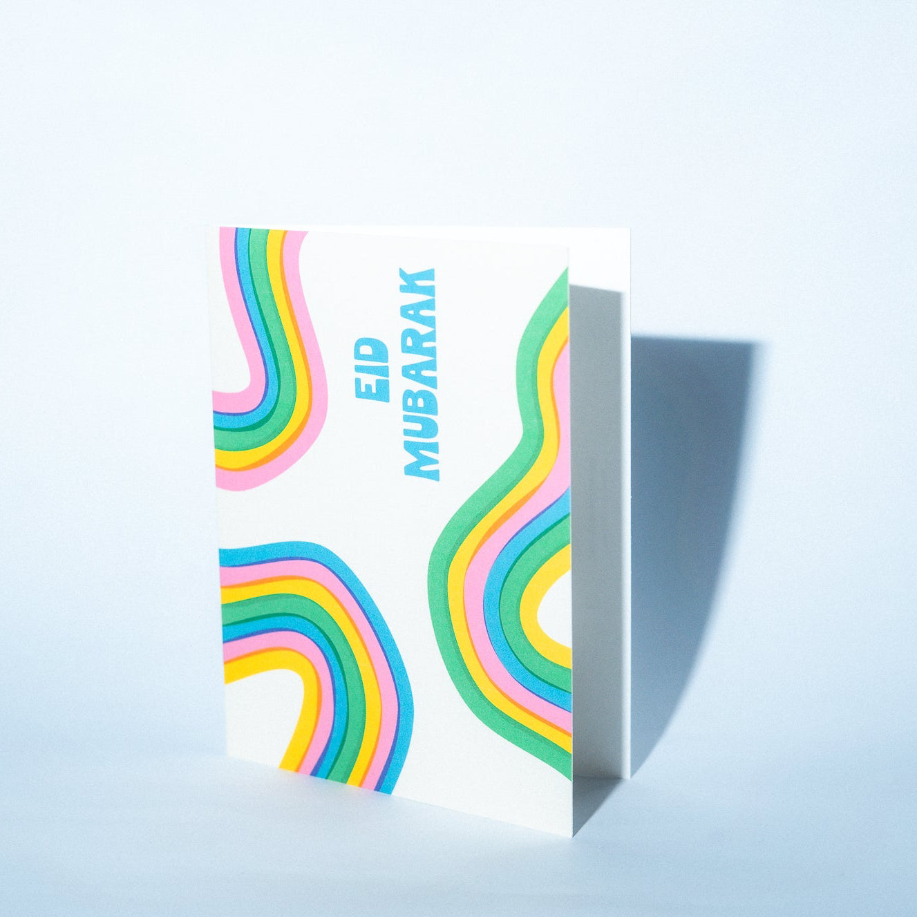Greeting card with colorful rainbow design and 'Eid Mubarak' text on a light blue background