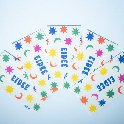 Colorful patterned paper cutout of a shirt with 'EIDEE' branding on a light blue background