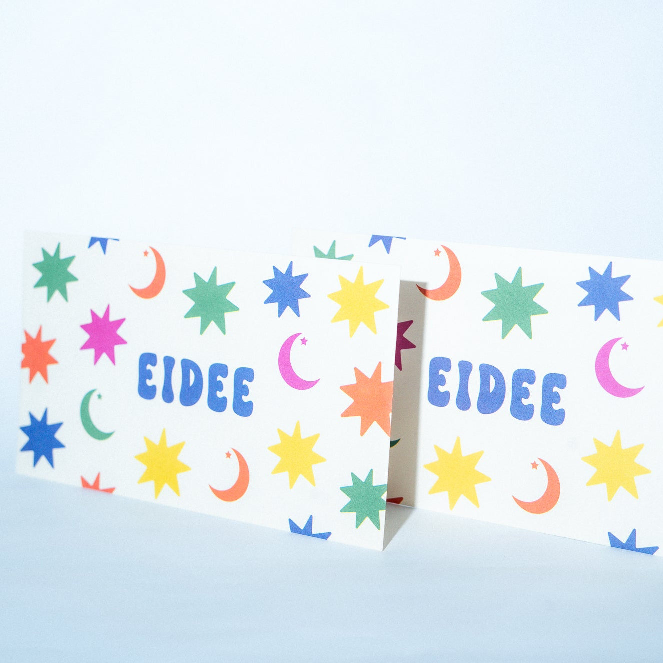 Colorful card with star and moon patterns and 'EIDEE' branding on a light blue background