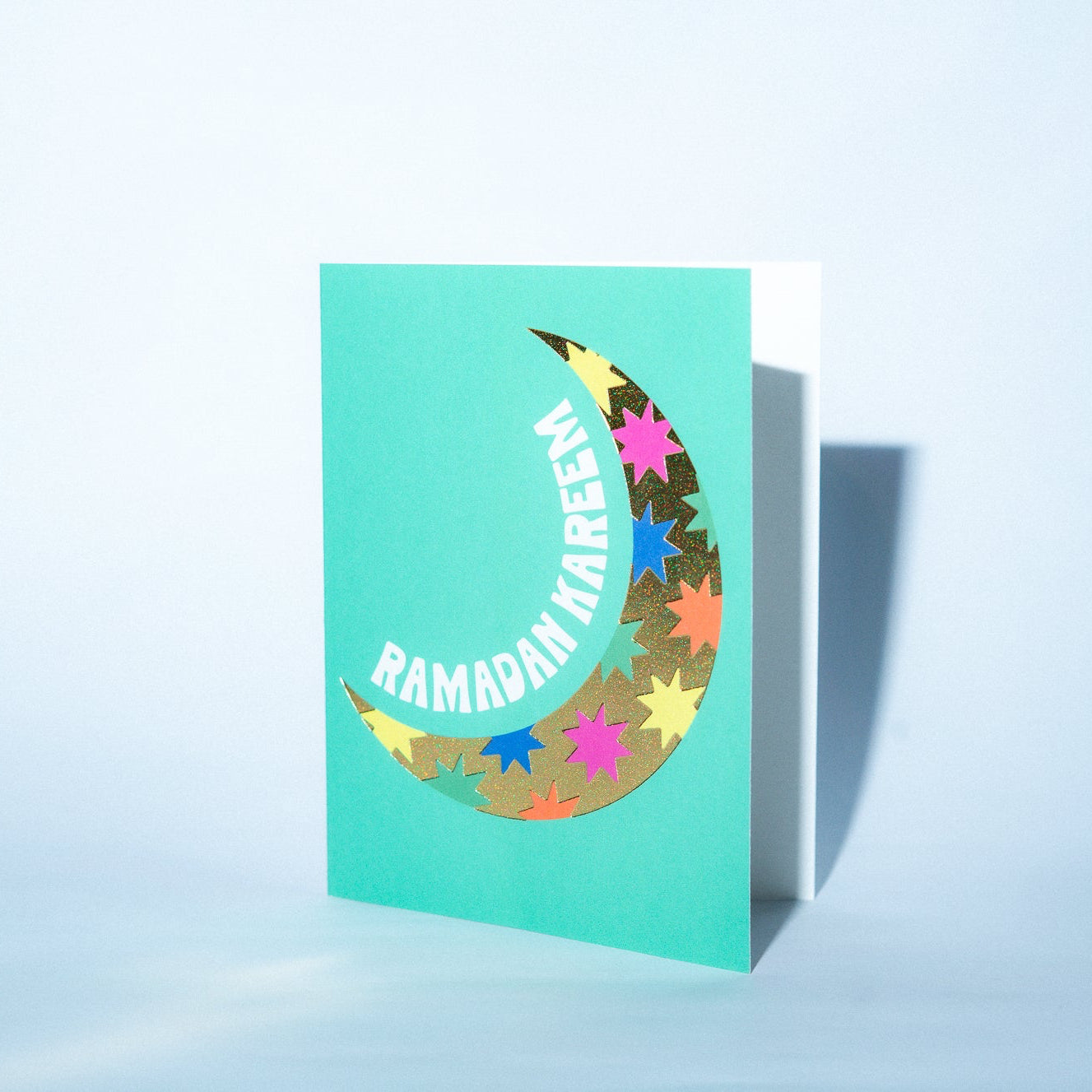 Greeting card with colorful moon and star design on a light blue background