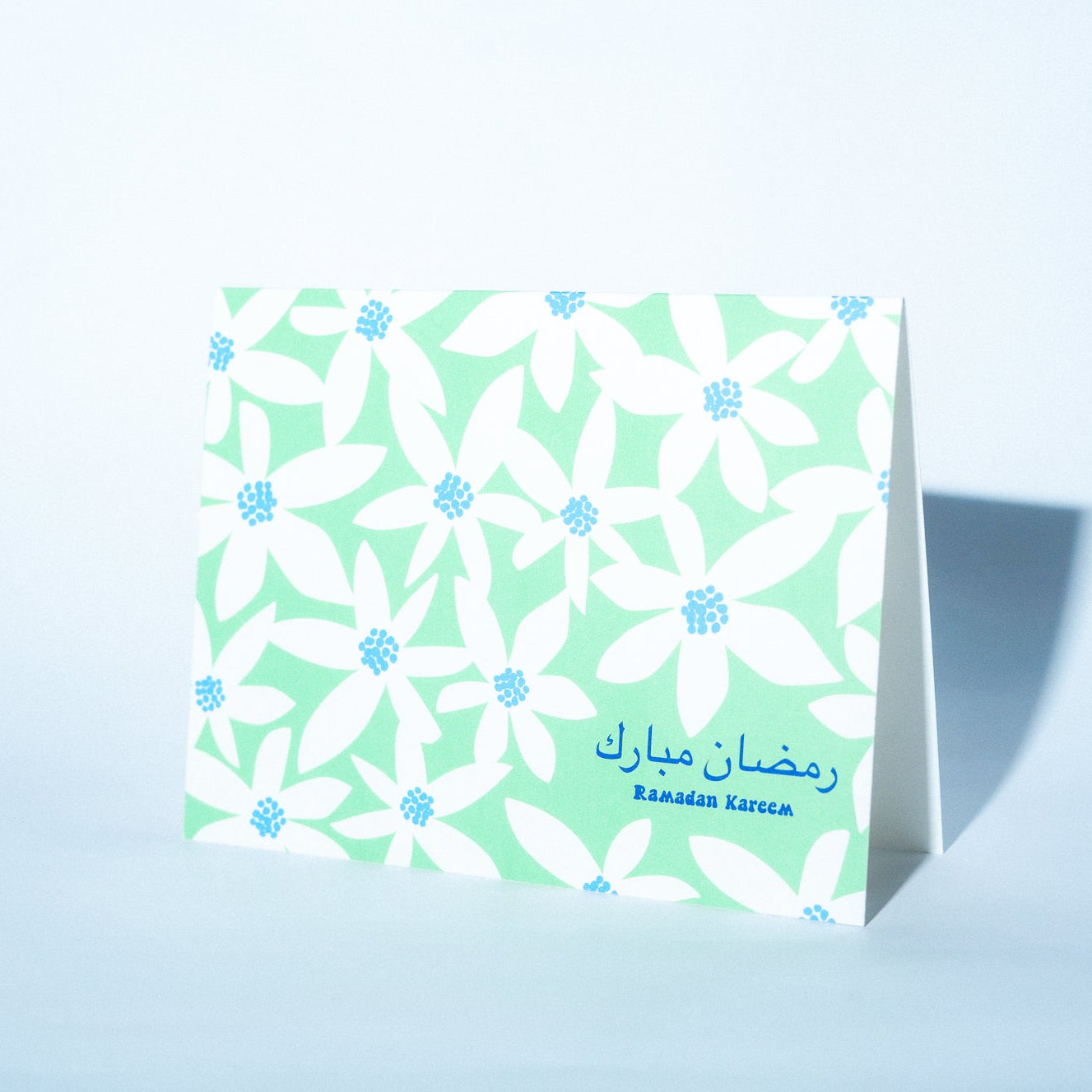 Floral patterned card with Arabic text on a light blue background