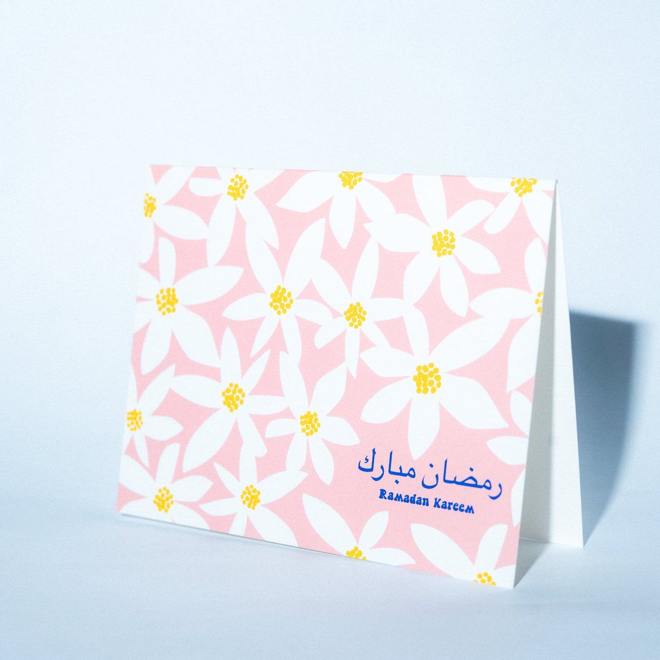 Greeting card with floral design and Arabic text on a light blue background