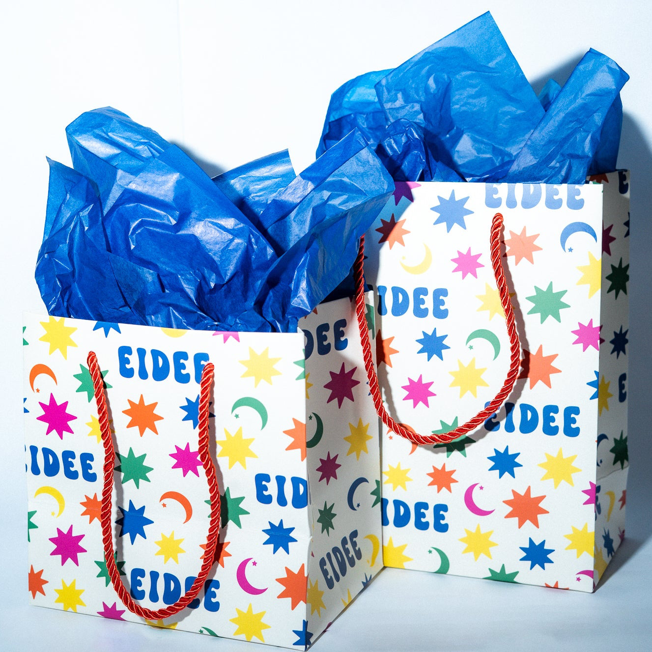 Gift bag with colorful star pattern and blue tissue paper on a white background