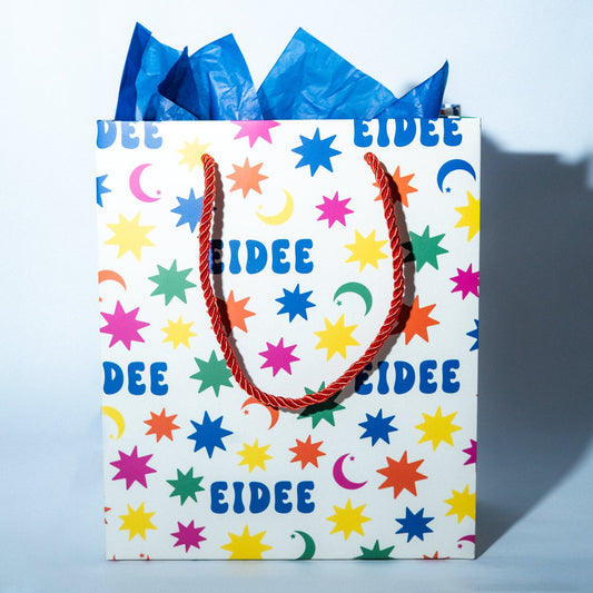 Colorful gift bag with 'EIDEE' branding on a light blue background