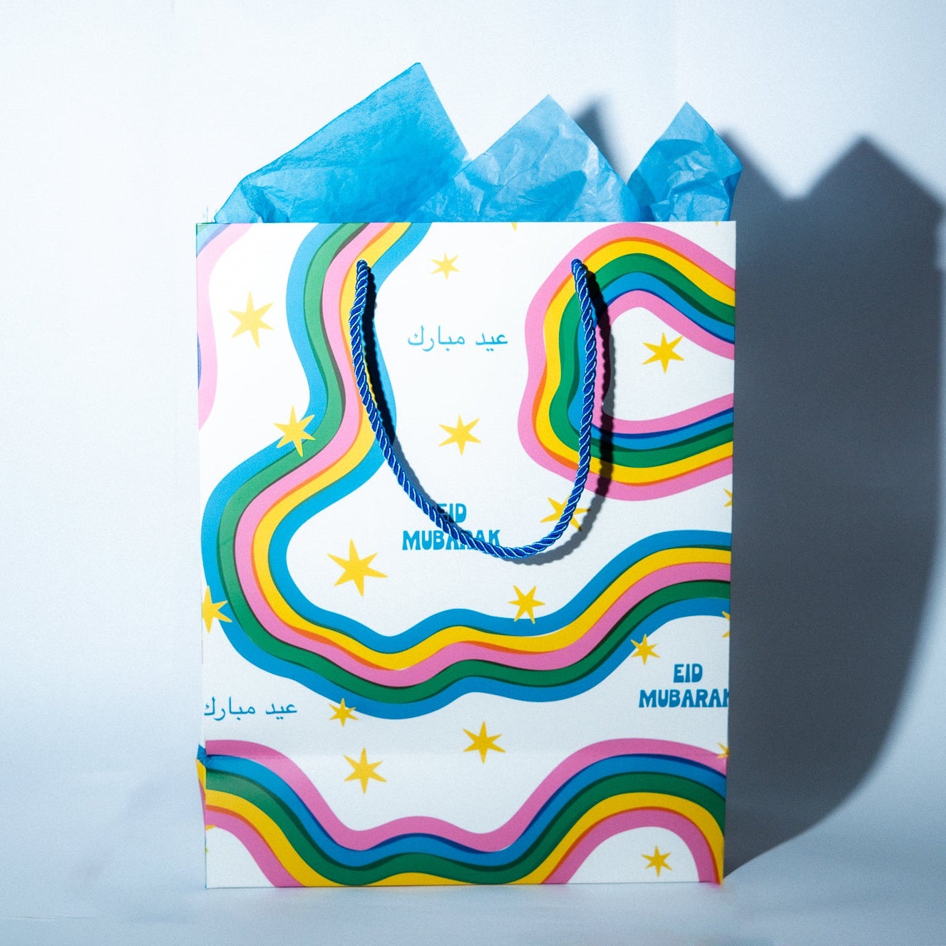 Gift bag with rainbow design and 'Eid Mubarak' text on a light blue background